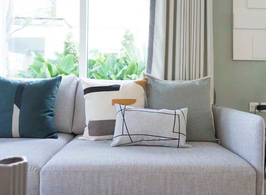 Green decorative pillows on a gray sofa by the window in the living room.