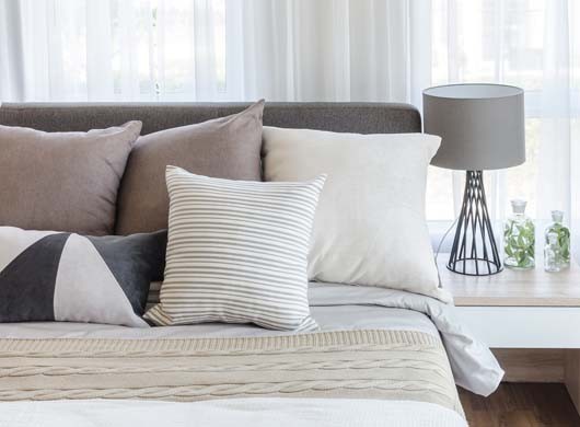 modern style bedroom with pillows on bed and modern grey lamp on side table at home