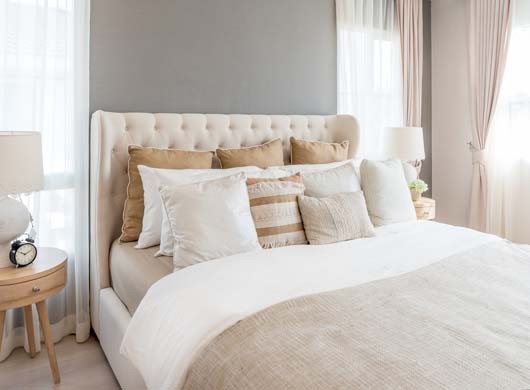 Bedroom in soft light colors. big comfortable double bed in elegant classic bedroom at home.
